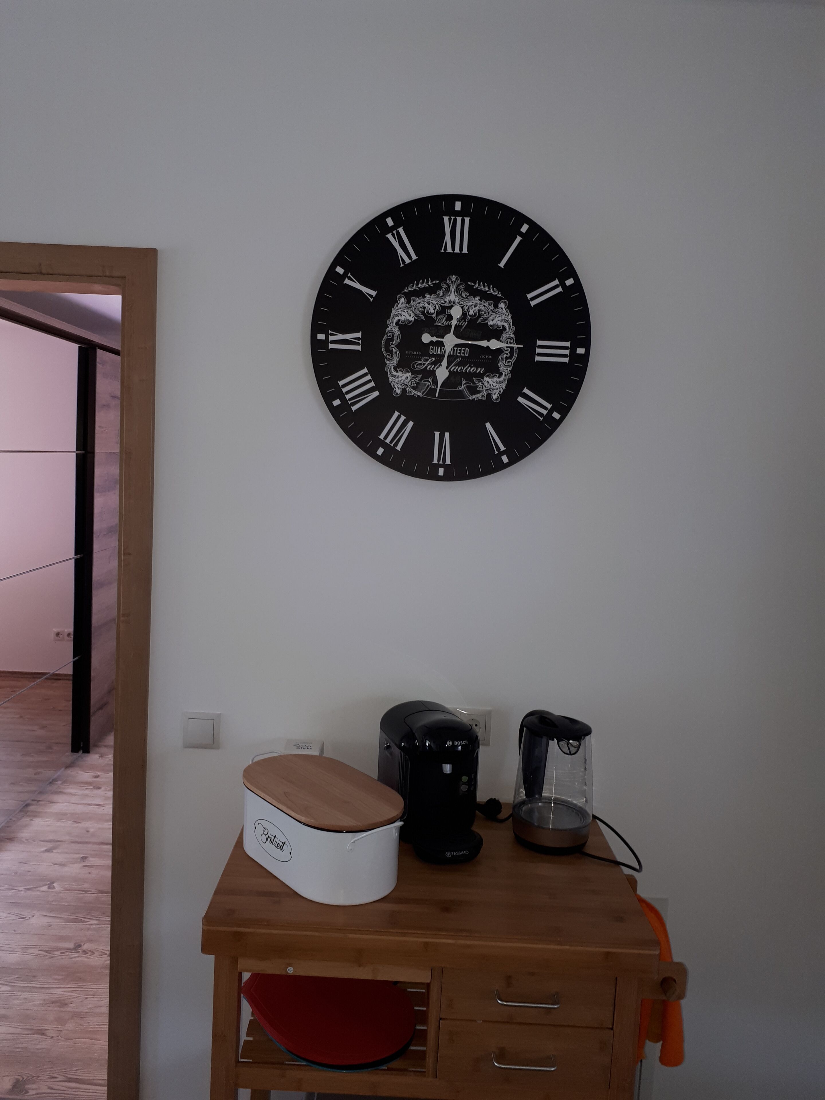 A room with a wooden cabinet, a Bosch coffee maker, and a glass carafe on a wooden countertop.