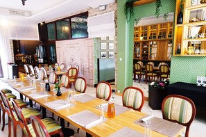 A dining area with a long wooden table set for a meal, surrounded by chairs with striped cushions. - Villa Tradycja (Bialystok)