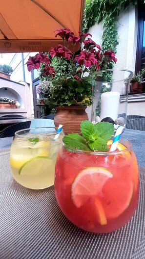 Two drinks with straws and mint leaves on a table with a potted plant in the background. - Villa Tradycja (Bialystok)