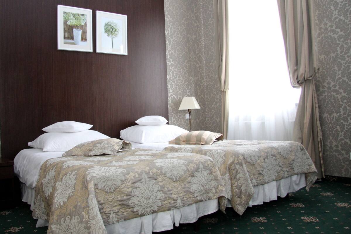 A hotel room with a large bed, a nightstand with a lamp, and two framed pictures on the wall.
