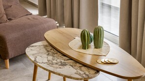 Un salon moderne avec une table basse ronde en bois, un banc en marbre, un canapé marron et deux cactus verts posés sur la table.