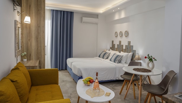 Une chambre d’hôtel moderne équipée d’un lit, d’un canapé, d’une table à manger et d’un petit coin cuisine.