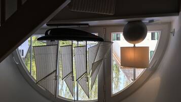Una habitación con tragaluz circular, lámpara colgante y vista a un edificio.