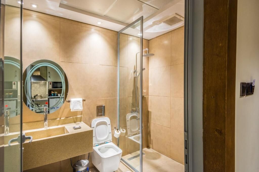 A modern bathroom with a glass-enclosed shower, a toilet, and a sink with a mirror.
