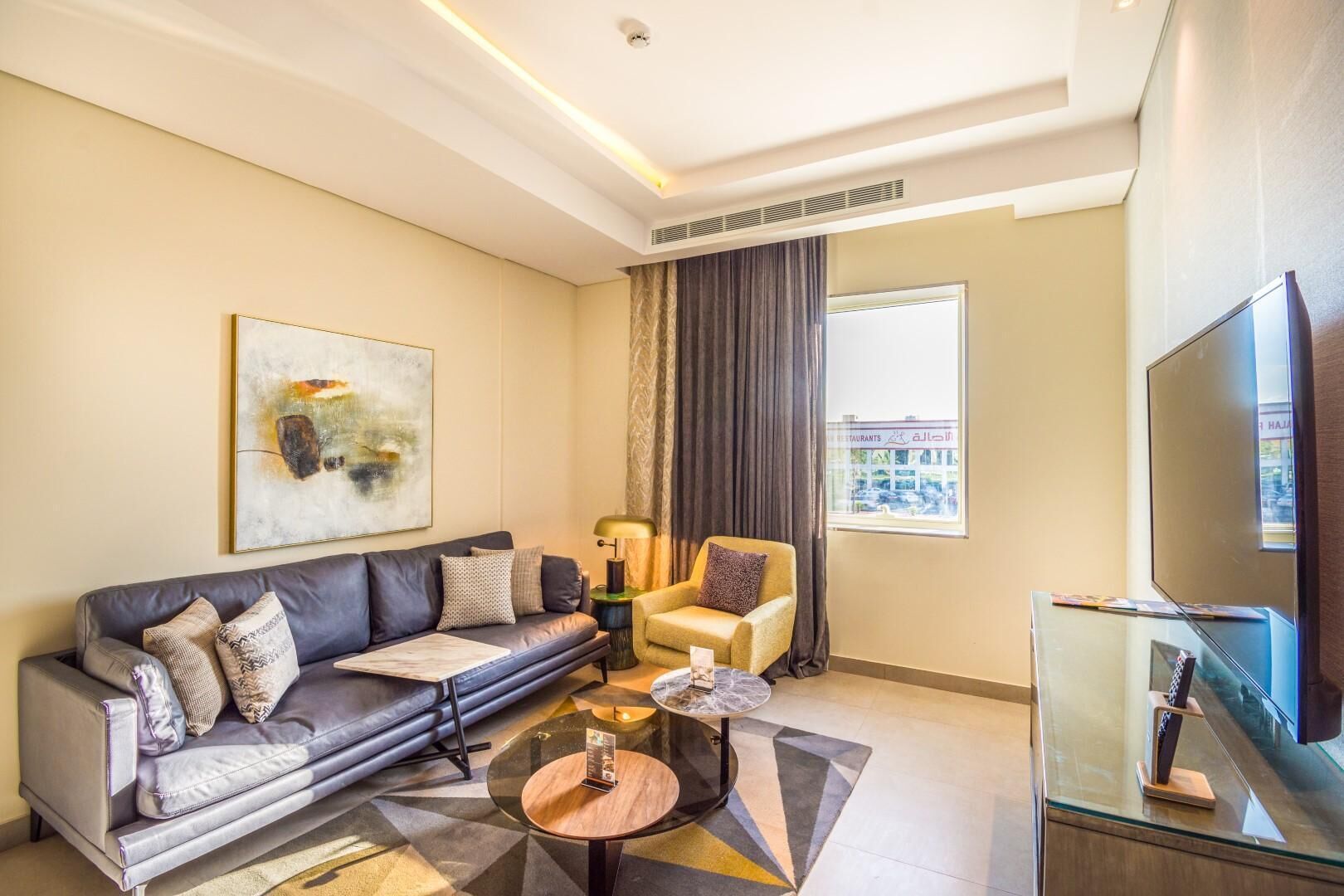 Una sala de estar moderna con sofá, sillón, mesa de centro y televisor.