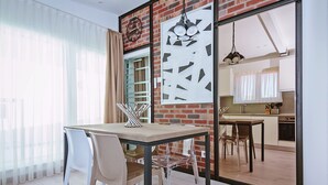 Un comedor con mesa y sillas, una pared de ladrillo y una cocina al fondo.