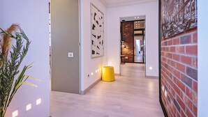 Un pasillo con diseño moderno, que incluye una silla de color amarillo, un panel decorativo y una pared de ladrillo.