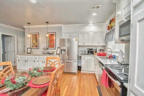 A modern kitchen with white cabinets, stainless steel appliances, and a dining area set for a meal.