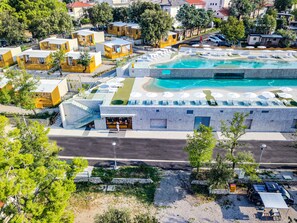 Vue aérienne d’un complexe hôtelier comprenant plusieurs hébergements de type bungalow, un espace piscine central et une allée pavée.