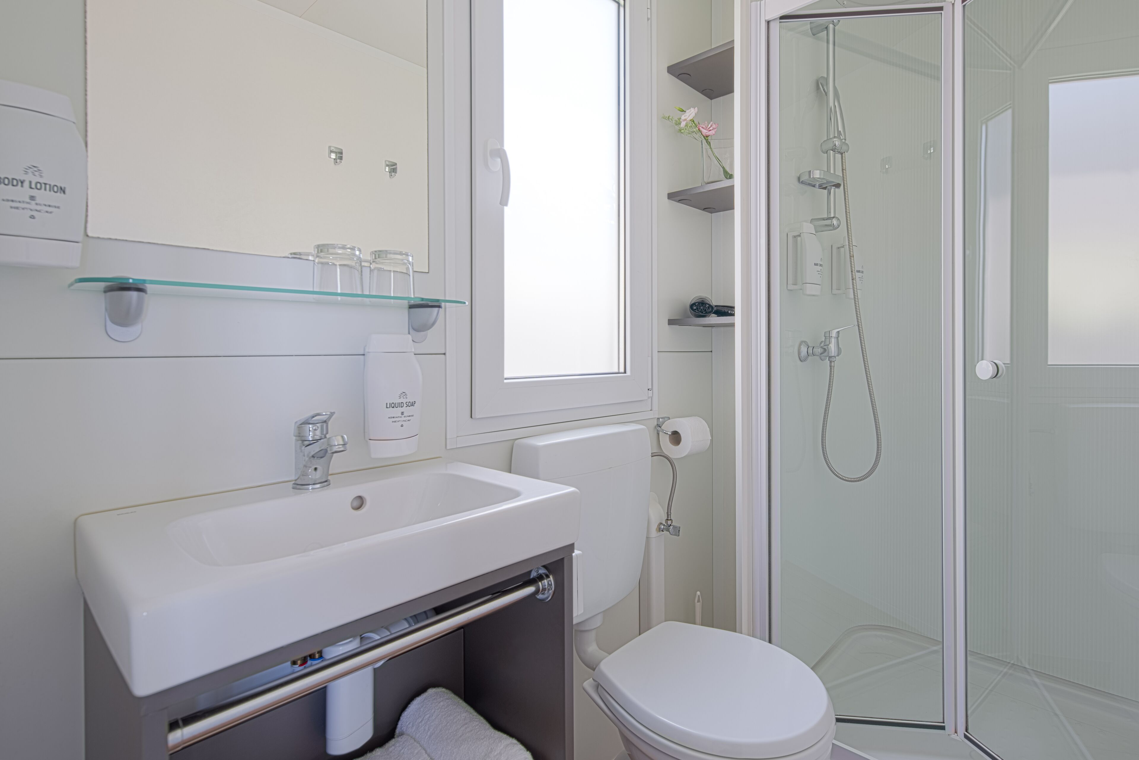 A modern bathroom with a white sink, toilet, and glass-enclosed shower.