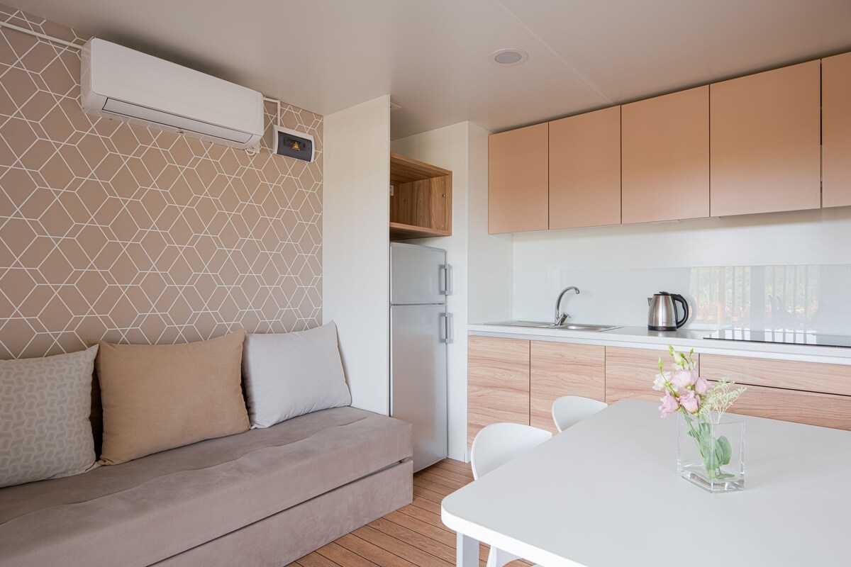 Une cuisine moderne dotée d’un four encastré, d’un réfrigérateur blanc et de meubles de rangement en bois.