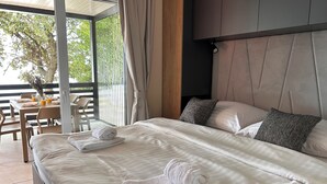 Een moderne slaapkamer met een groot bed, twee kussens en een netjes opgemaakt witte handdoek.