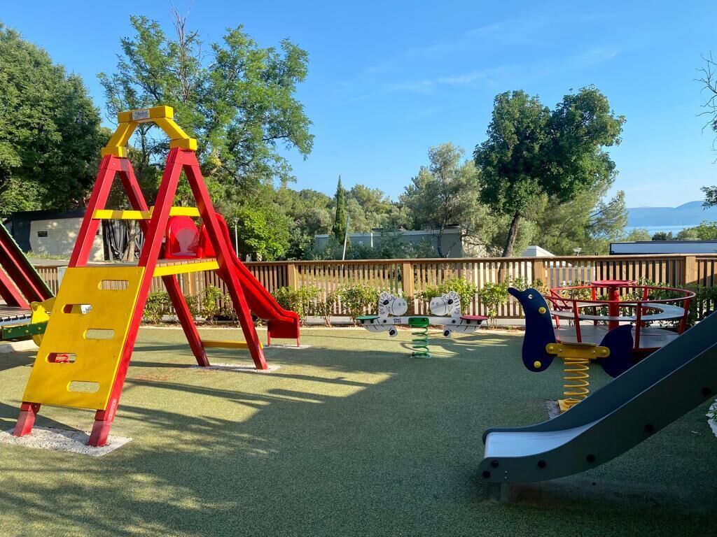 Un parque infantil con tobogán, estructura de escalada y columpios.