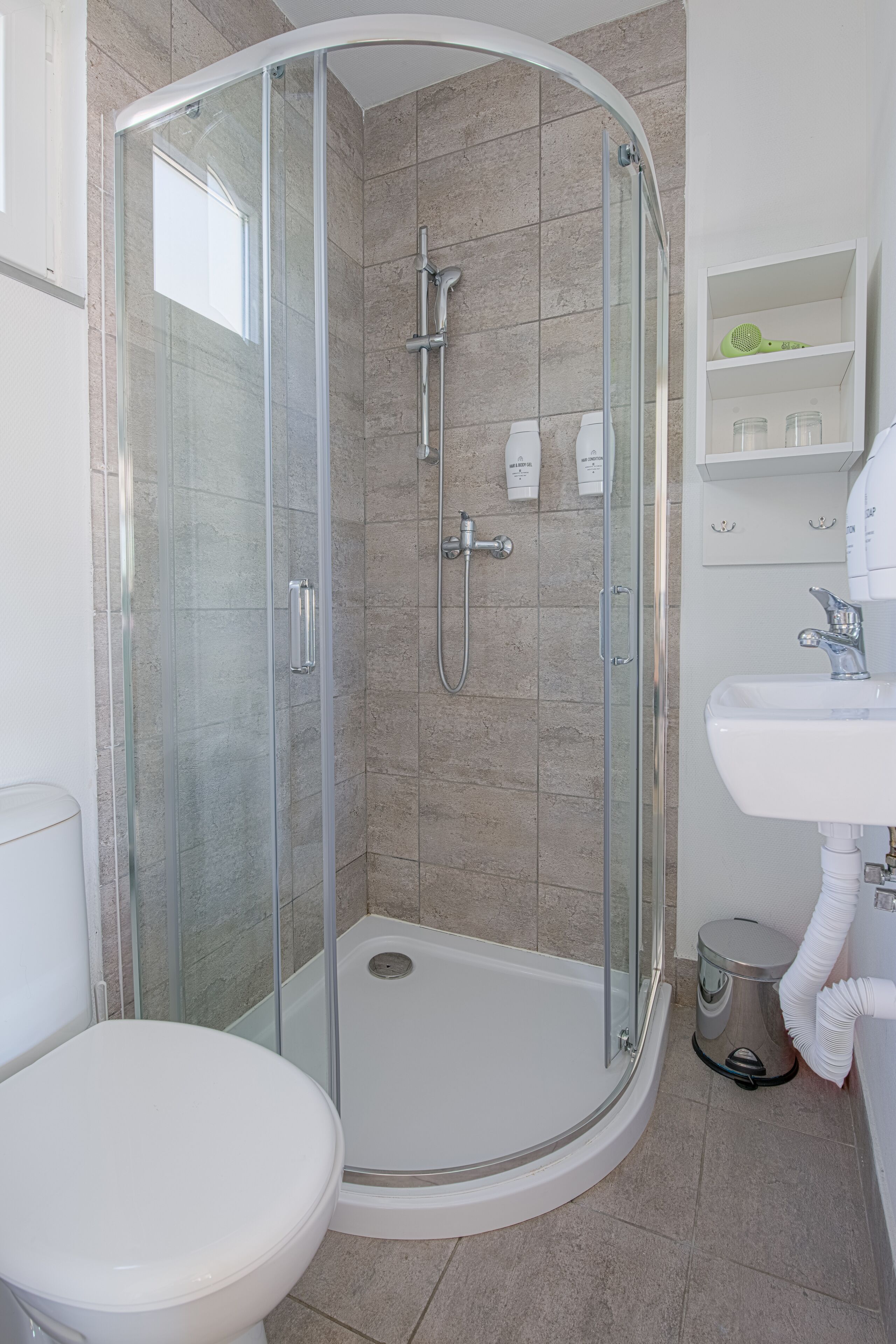 A modern bathroom with a glass-enclosed shower, a white toilet, and a sink with a mirror.