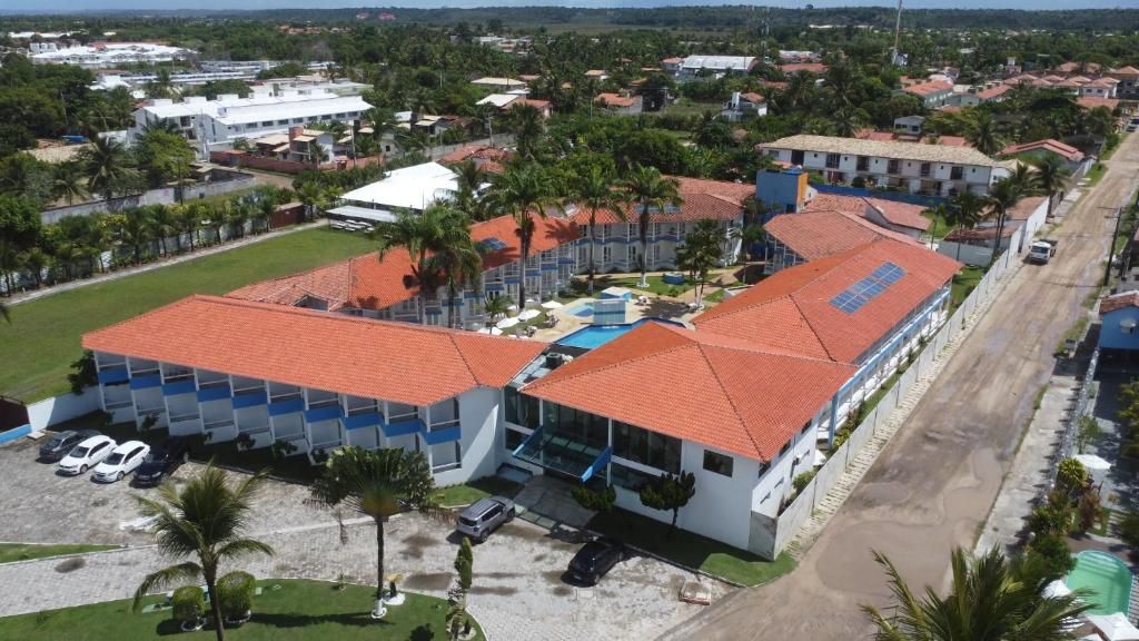 Un grand bâtiment avec un toit recouvert de tuiles rouges, de nombreuses places de stationnement et une piscine.