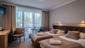 A hotel room with two beds, a desk, a chair, and a small table. - Hotel NAT Jaroslawiec (Postomino)