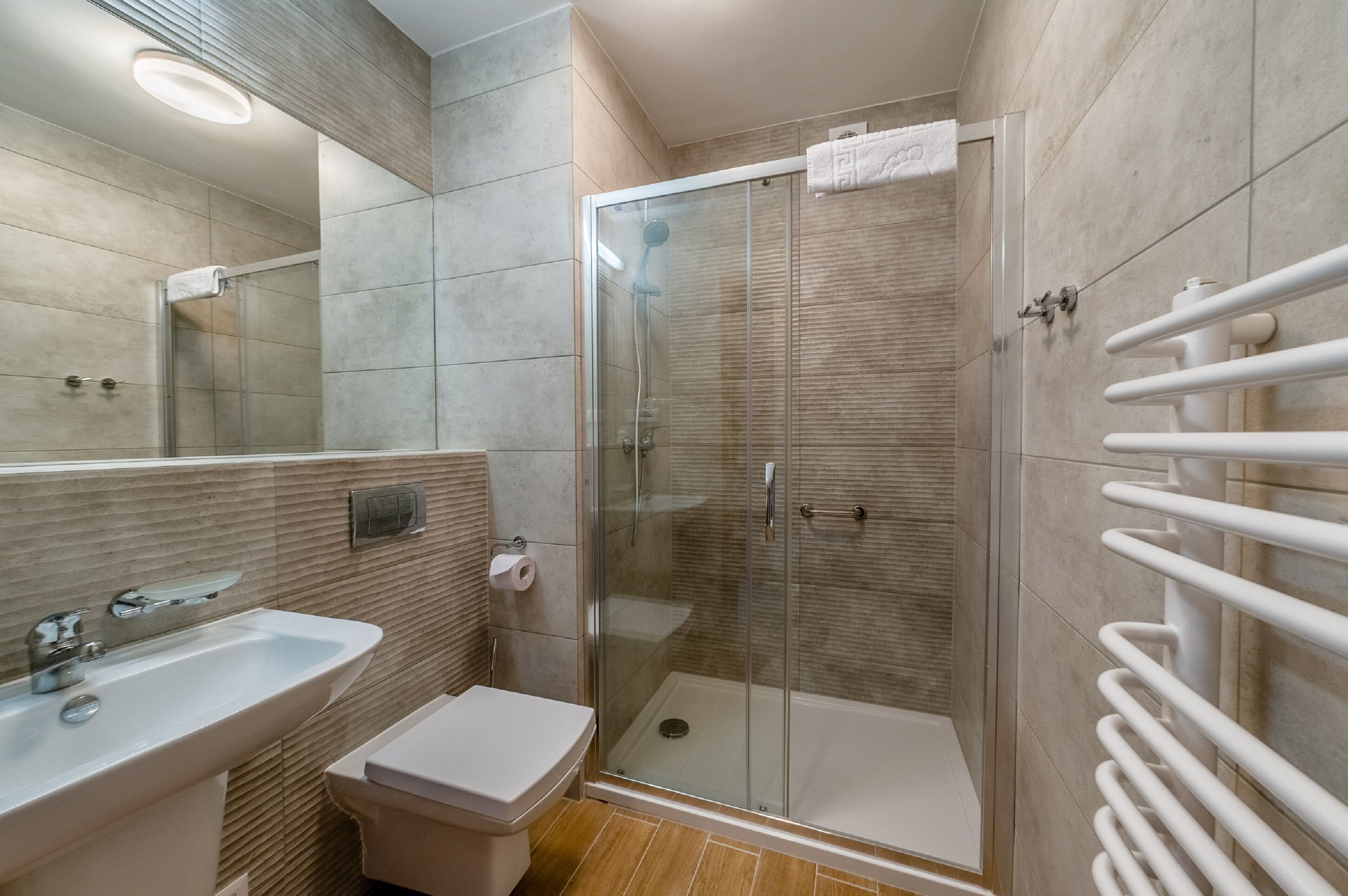 A modern bathroom with a glass-enclosed shower, a sink, and a toilet.