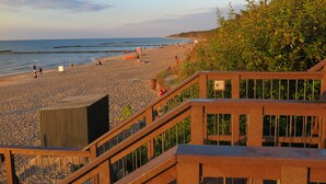 A beach with a wooden walkway leading to the shore, a lifeguard tower, and a clear view of the sea. - Hotel NAT Jaroslawiec (Postomino)