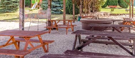 An outdoor seating area with picnic tables and a fire pit.