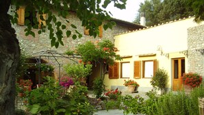 Ein Innenhof mit Steinmauern, Kübelpflanzen und einer Pergola.