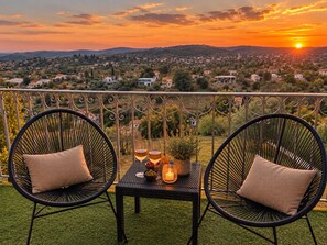 Un balcón con dos sillas, una mesa y vistas al atardecer.