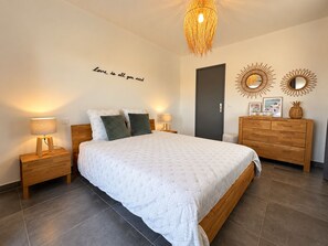 Un dormitorio con cama, lámparas de noche, cómoda y decoración de pared.
