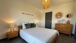 Un dormitorio con cama, mesitas de noche, cómoda, puerta y decoración en la pared.