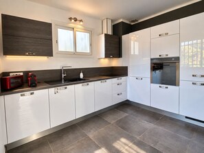 Eine moderne Küche mit weißen Schränken, einer schwarzen Arbeitsplatte, einem eingebauten Backofen und einem Fenster über der Spüle.