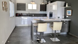 Una cocina moderna con una isla central, electrodomésticos de acero inoxidable e iluminación colgante.