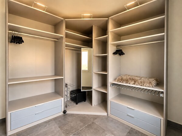 A walk-in closet with multiple shelves, a hanging rack, and a small storage bin.