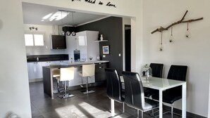 Una cocina moderna con armarios blancos, una zona de comedor con sillas negras y una decoración de rama montada en la pared.