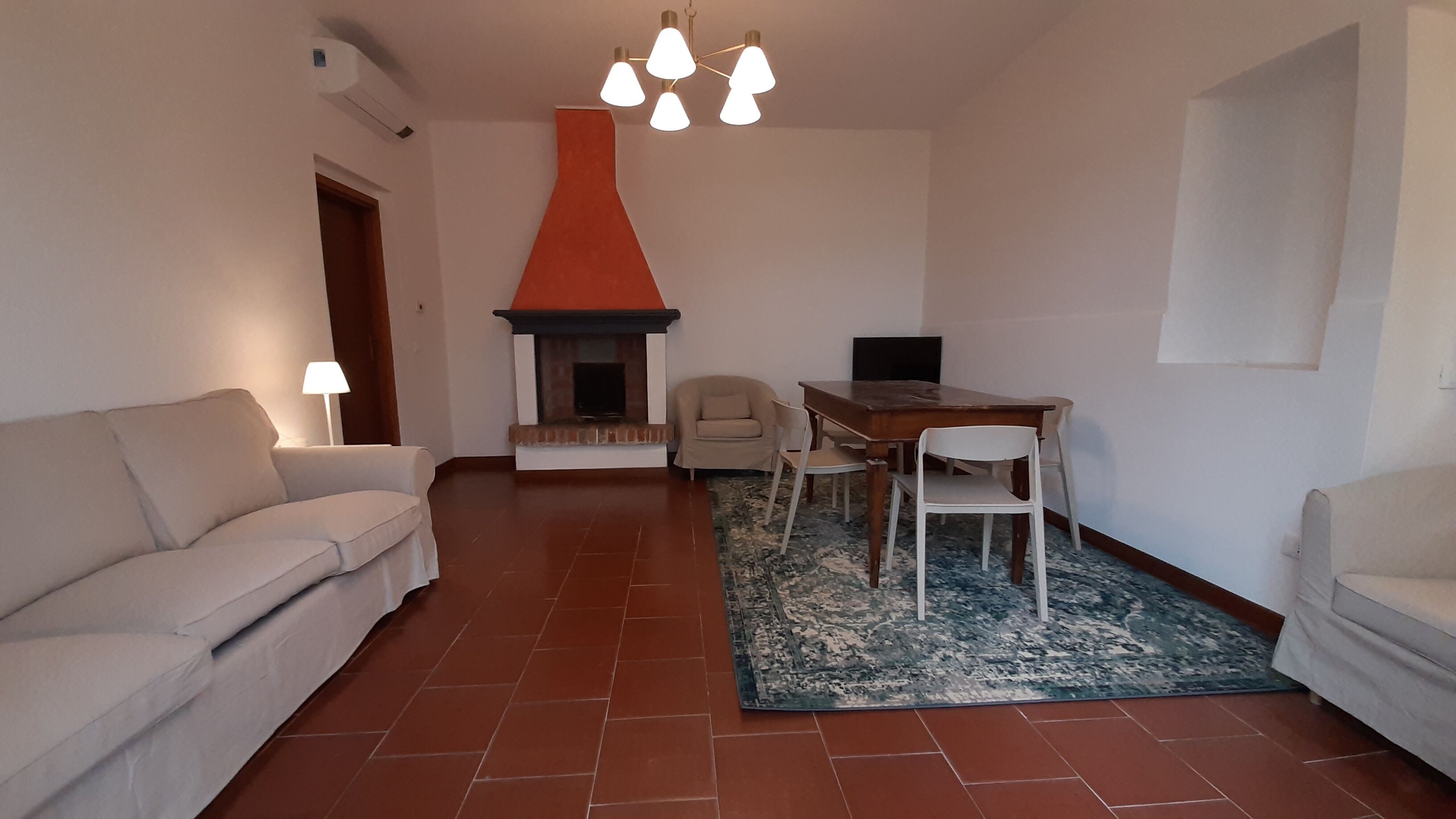 Un salon comprenant un canapé, une table, une chaise, une cheminée et un tapis à motifs.