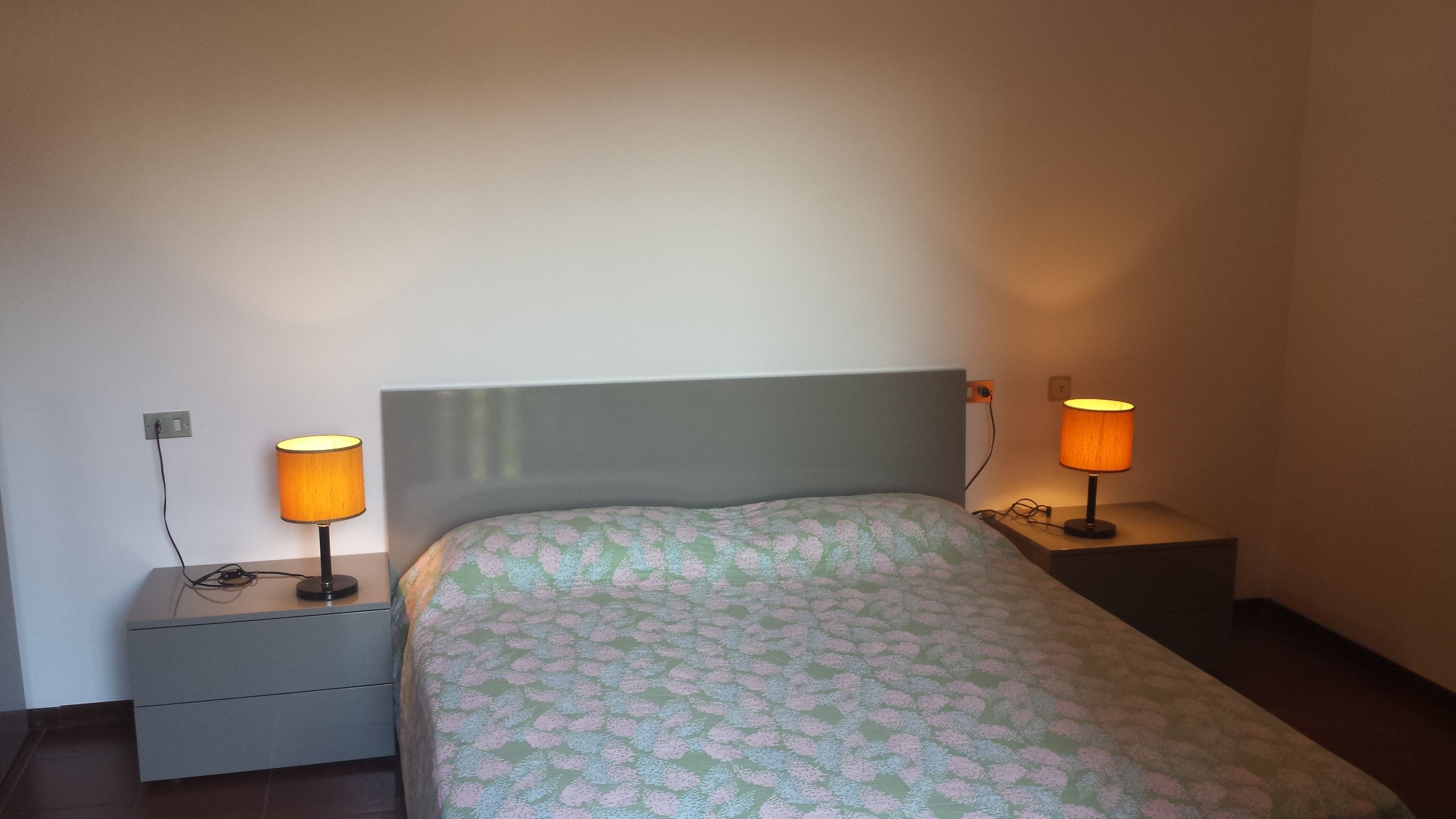 Ein Schlafzimmer mit einem Bett, zwei Nachttischen und zwei Lampen.