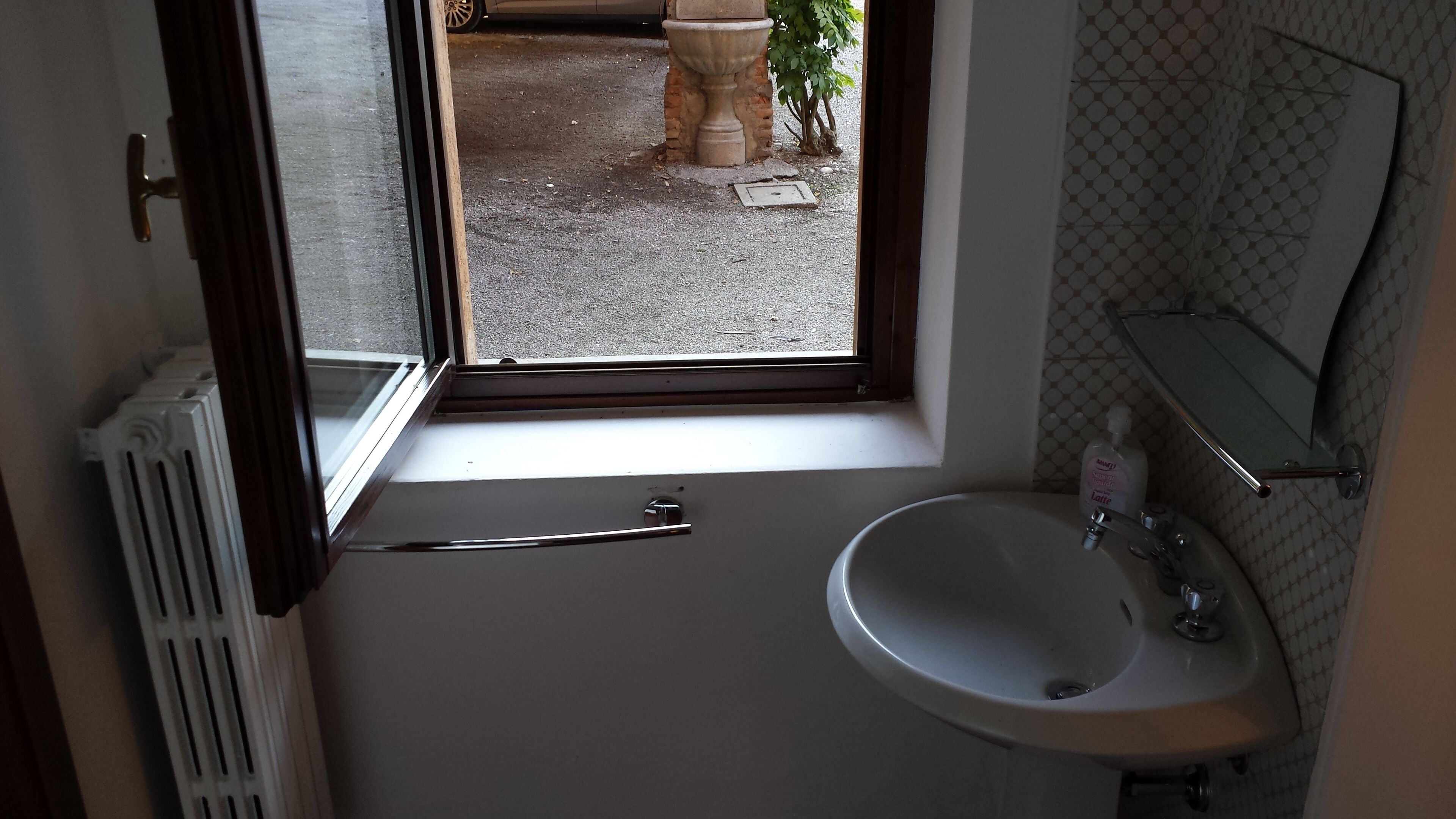 A bathroom with a window, a sink, and a radiator.