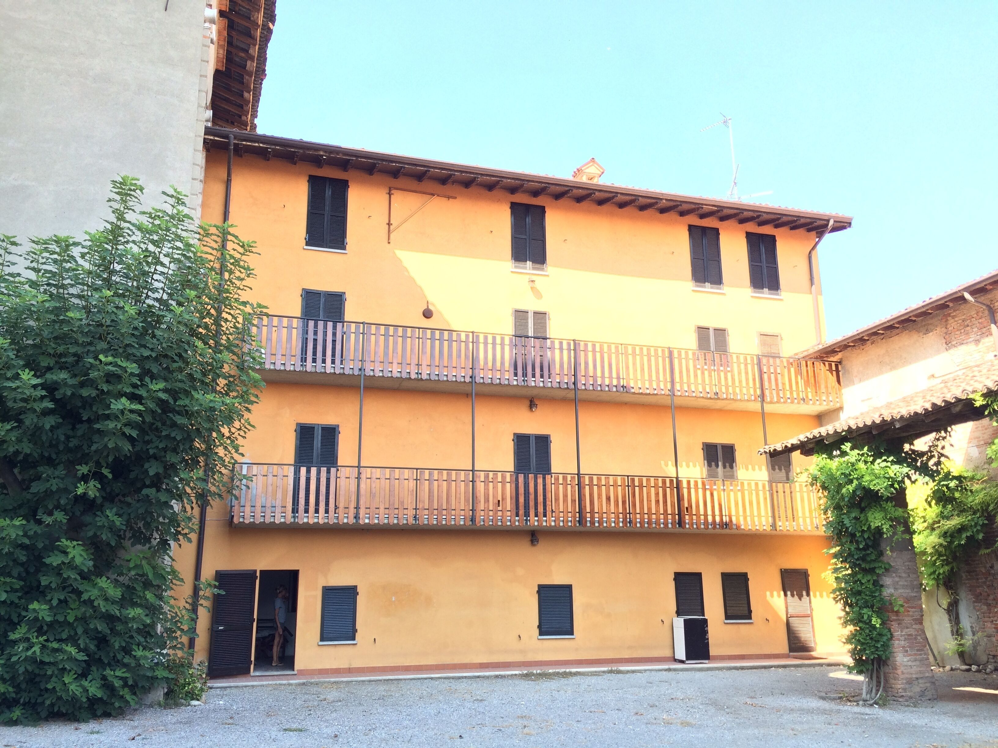 A multi-story building with balconies and a gravel courtyard.