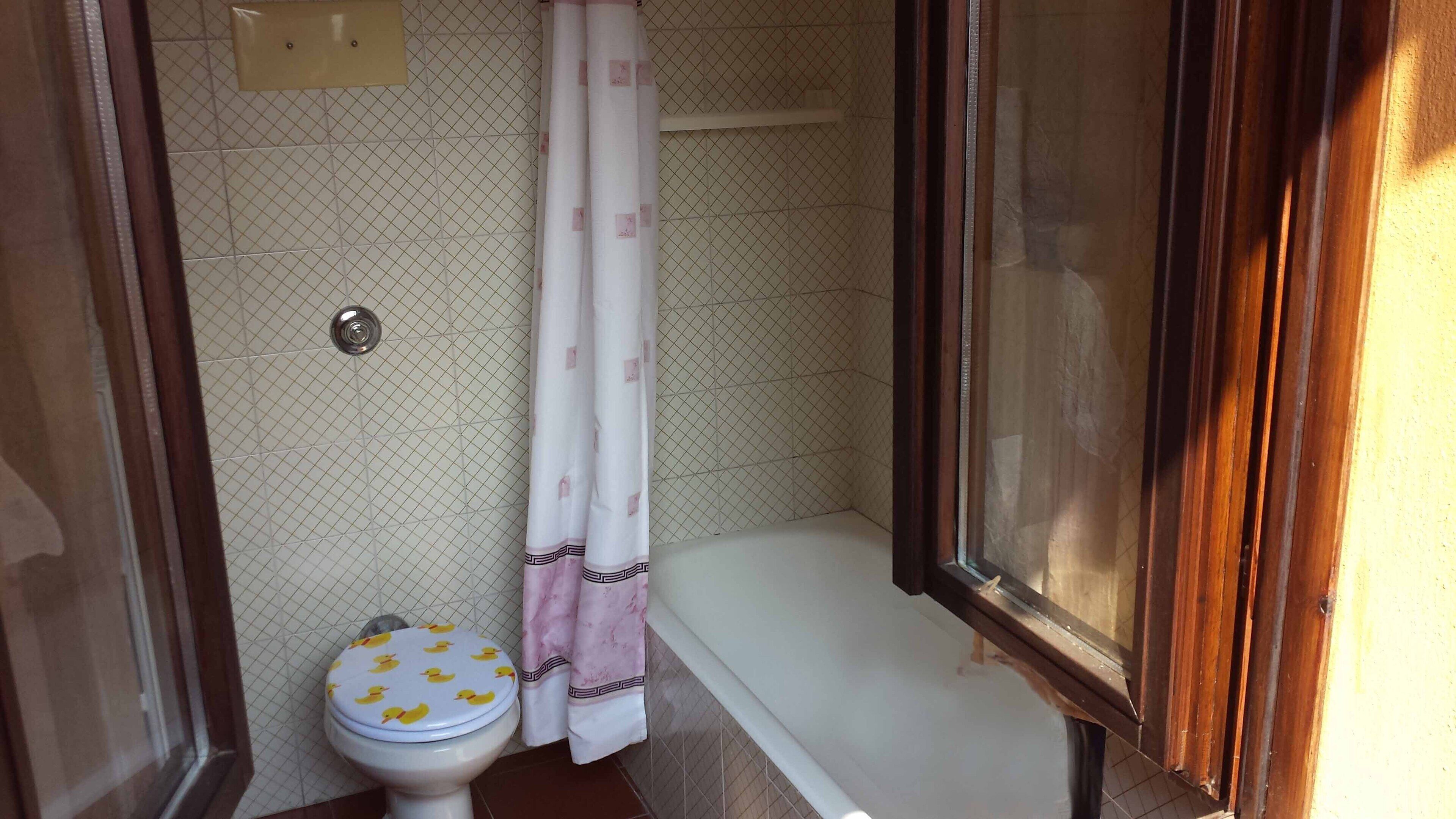 A small bathroom with a toilet, a shower, and a bathtub.