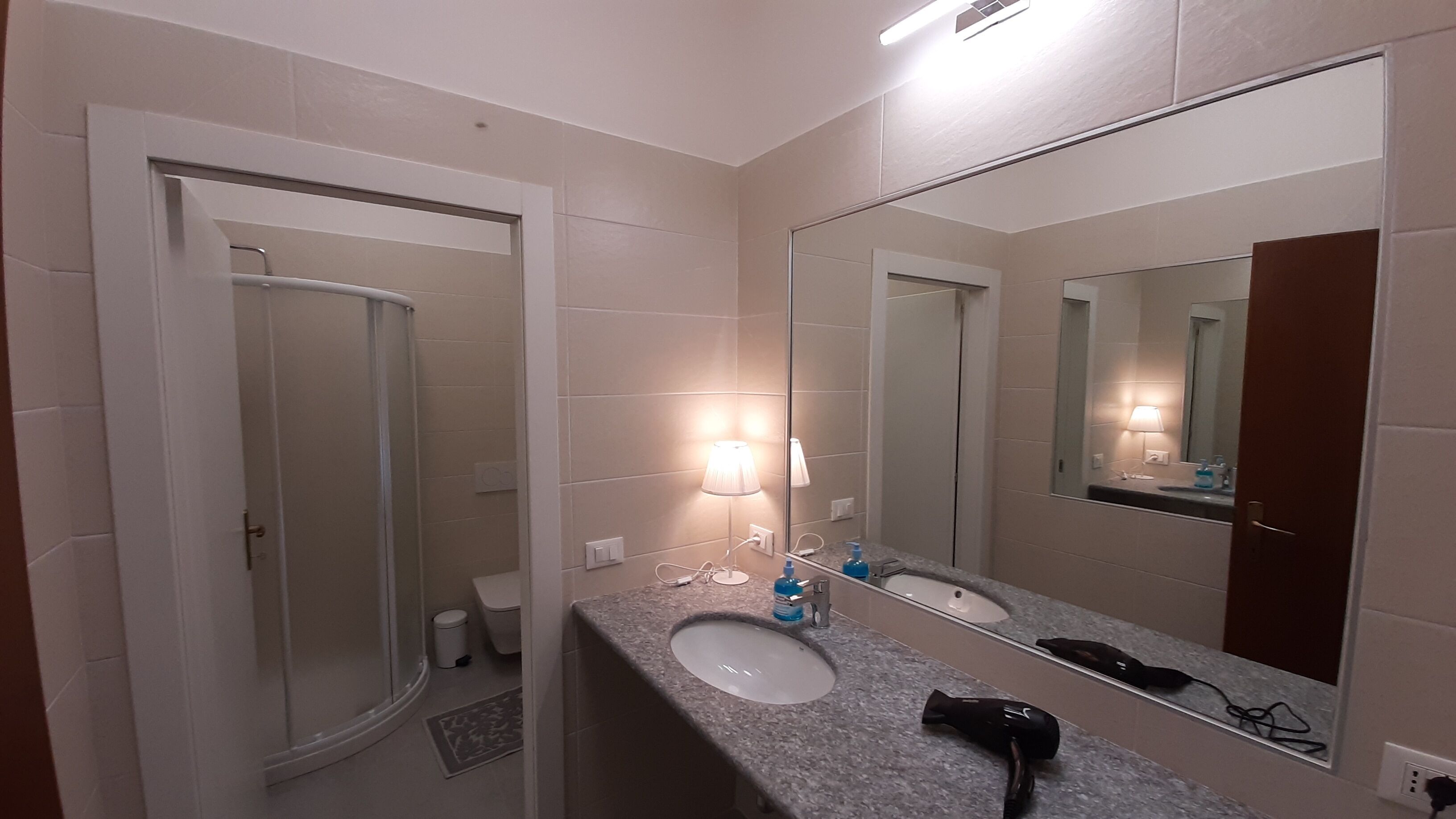 A bathroom with a sink, mirror, and a hairdryer on the counter.
