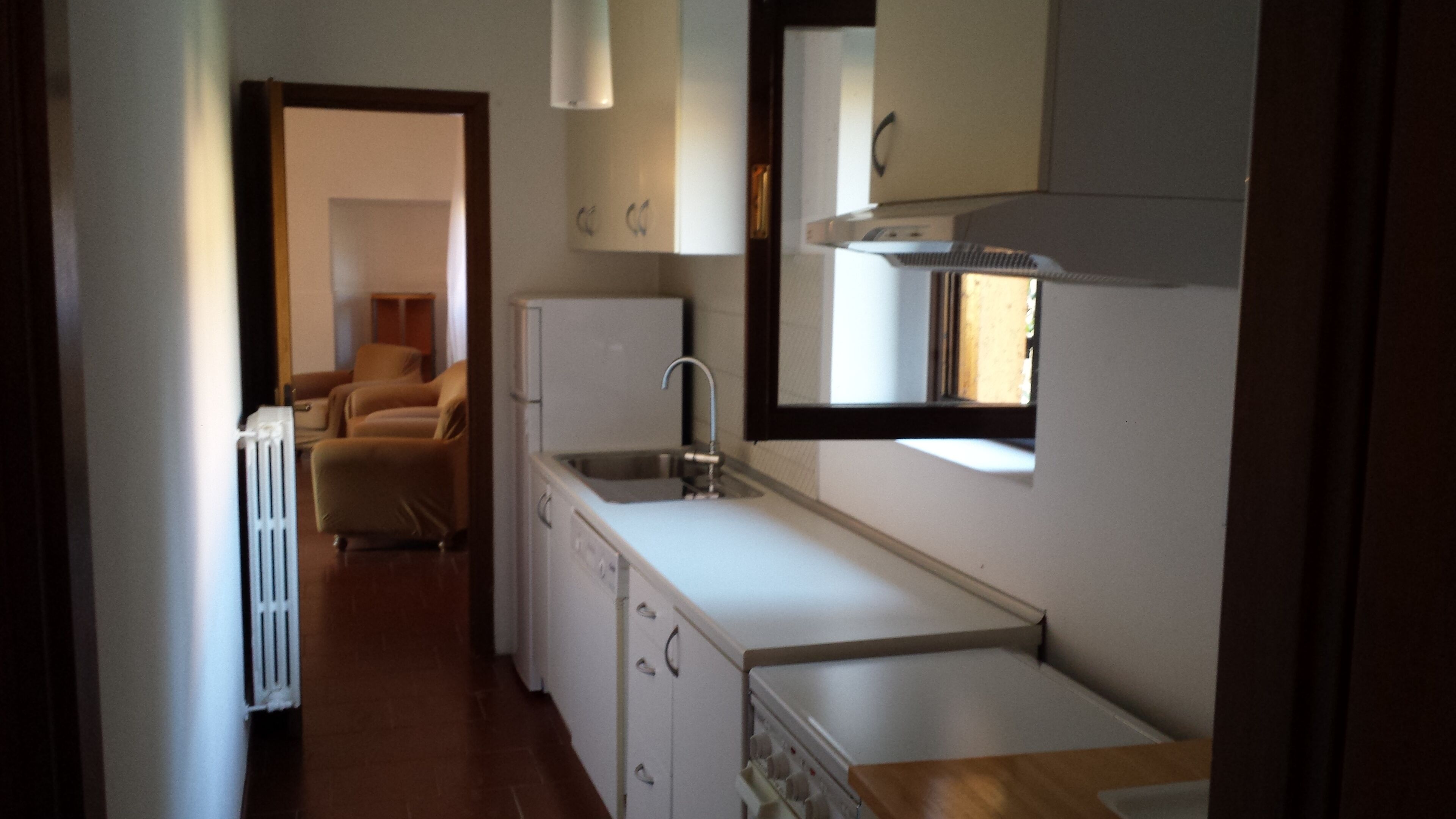 Eine kleine Küche mit Spüle, Kühlschrank und einem Fenster über der Arbeitsfläche.