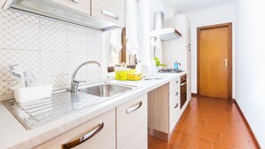 A modern kitchen with a double sink, white cabinets, and a wooden door. - Palazzo Barbò (Torre Pallavicina)