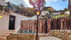 A stone wall with a wooden fence, a lamp post, and a staircase leading to a balcony.