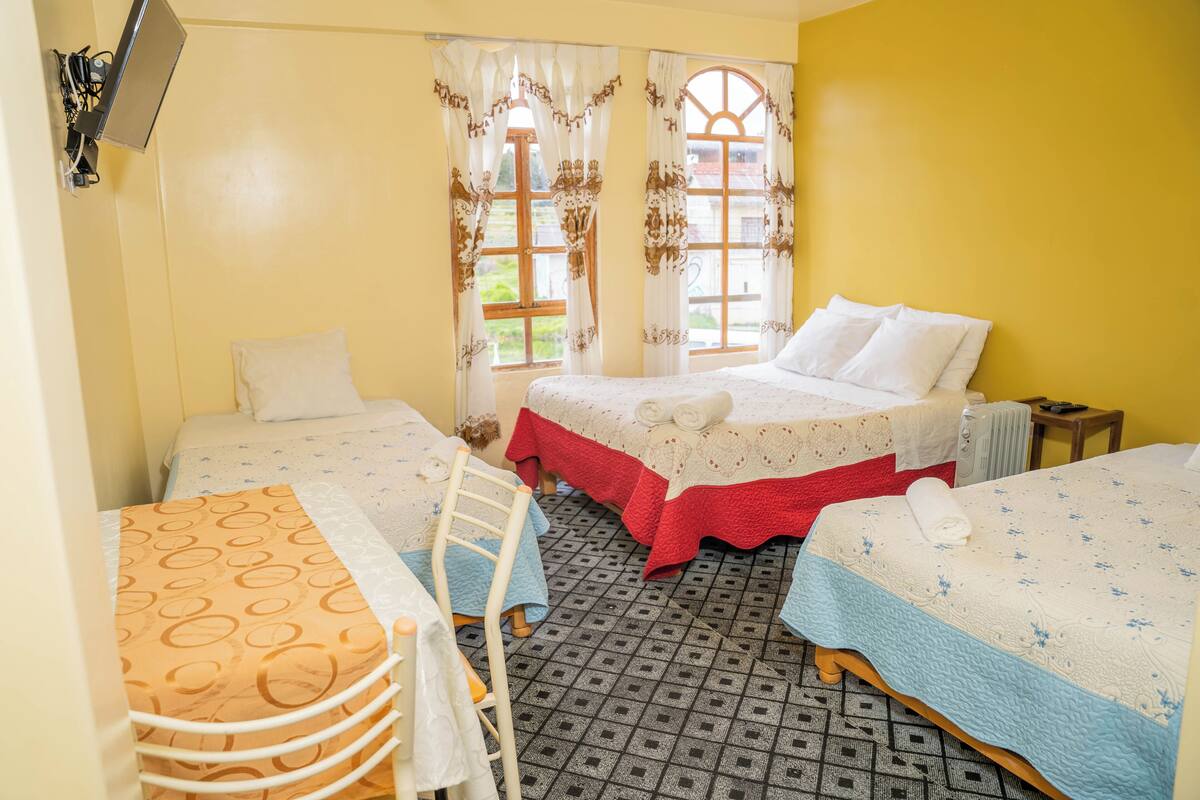 A room with two beds, a table, and a chair.