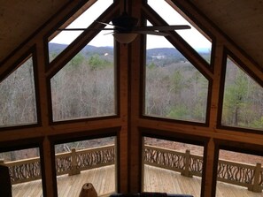 Una habitación con un gran techo de madera y varias ventanas que ofrecen vistas a un paisaje boscoso.