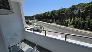 Uma varanda com vista para uma estrada, árvores e uma placa com a inscrição 'BAZAAR'.