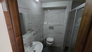 Um banheiro compacto com pia, espelho e vaso sanitário brancos.