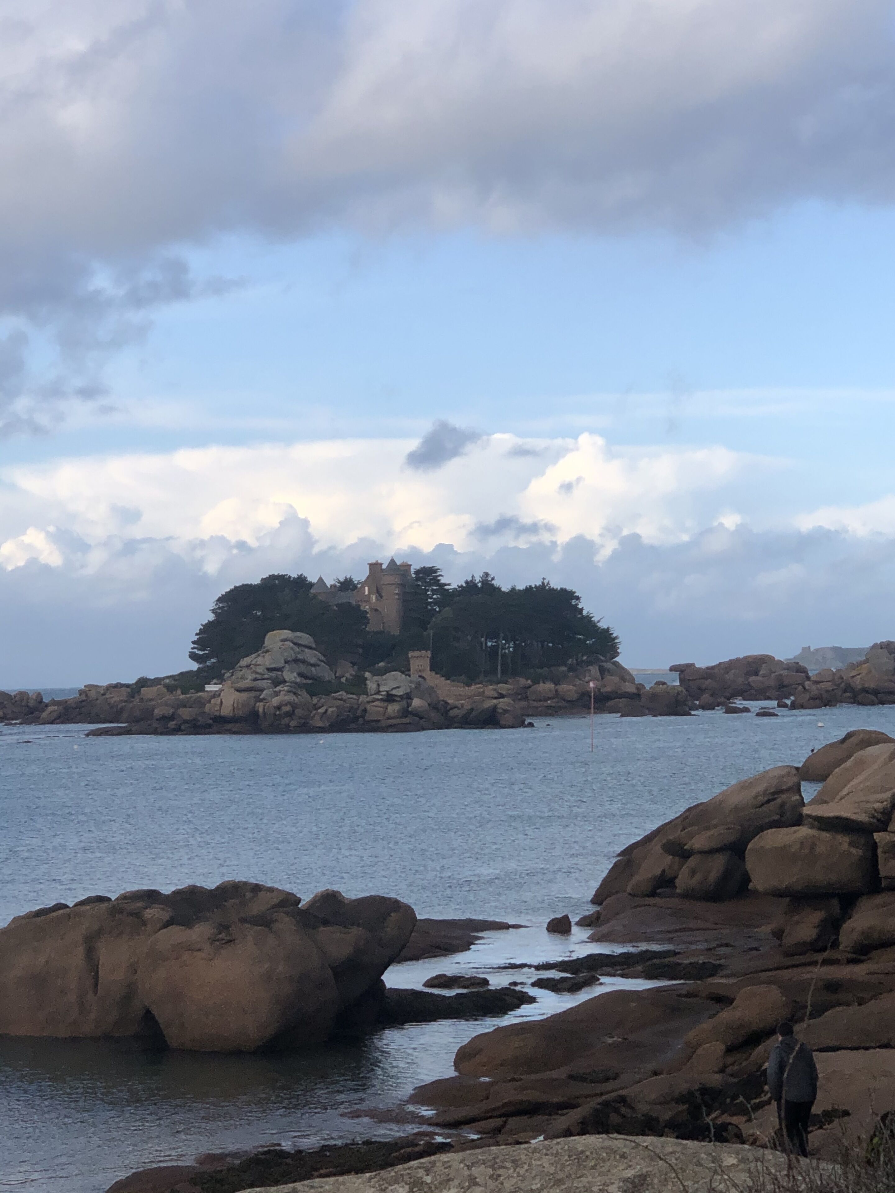 Un paisaje costero con formaciones rocosas y una estructura similar a un castillo en una pequeña isla.