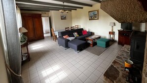 Un salon comprenant un canapé, une table basse, une cheminée et un coin repas avec des chaises et une table.