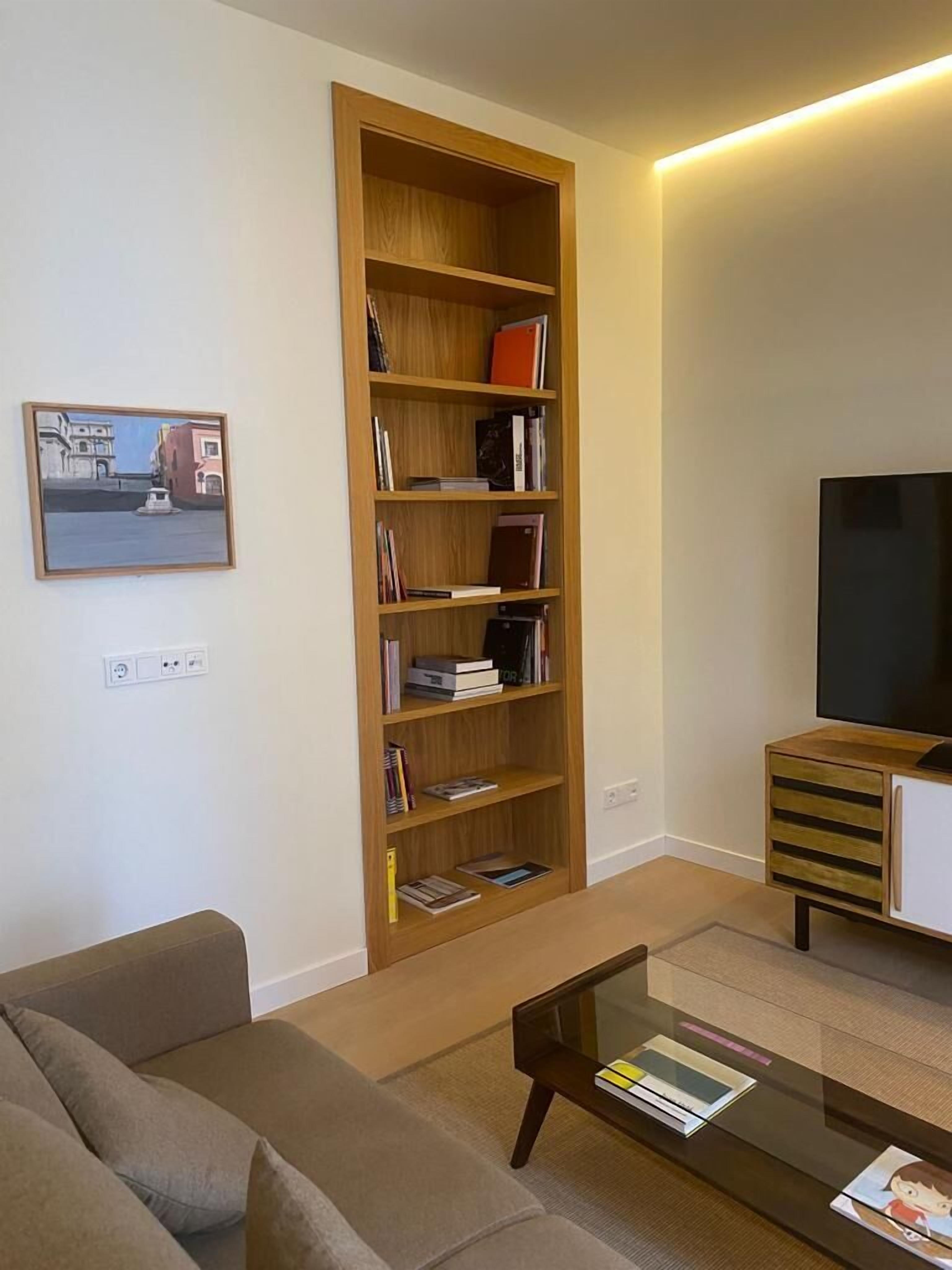 A living room with a wooden bookshelf, a flat-screen TV, a sofa, and a coffee table.
