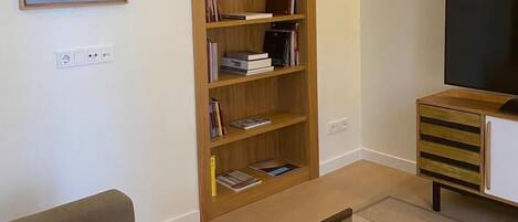 A living room with a wooden bookshelf, a flat-screen TV, a sofa, and a coffee table.