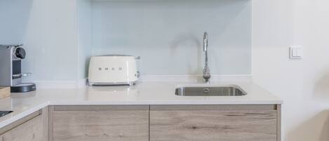 A modern kitchen with wooden cabinets, a built-in microwave, a toaster, and a stainless steel sink.