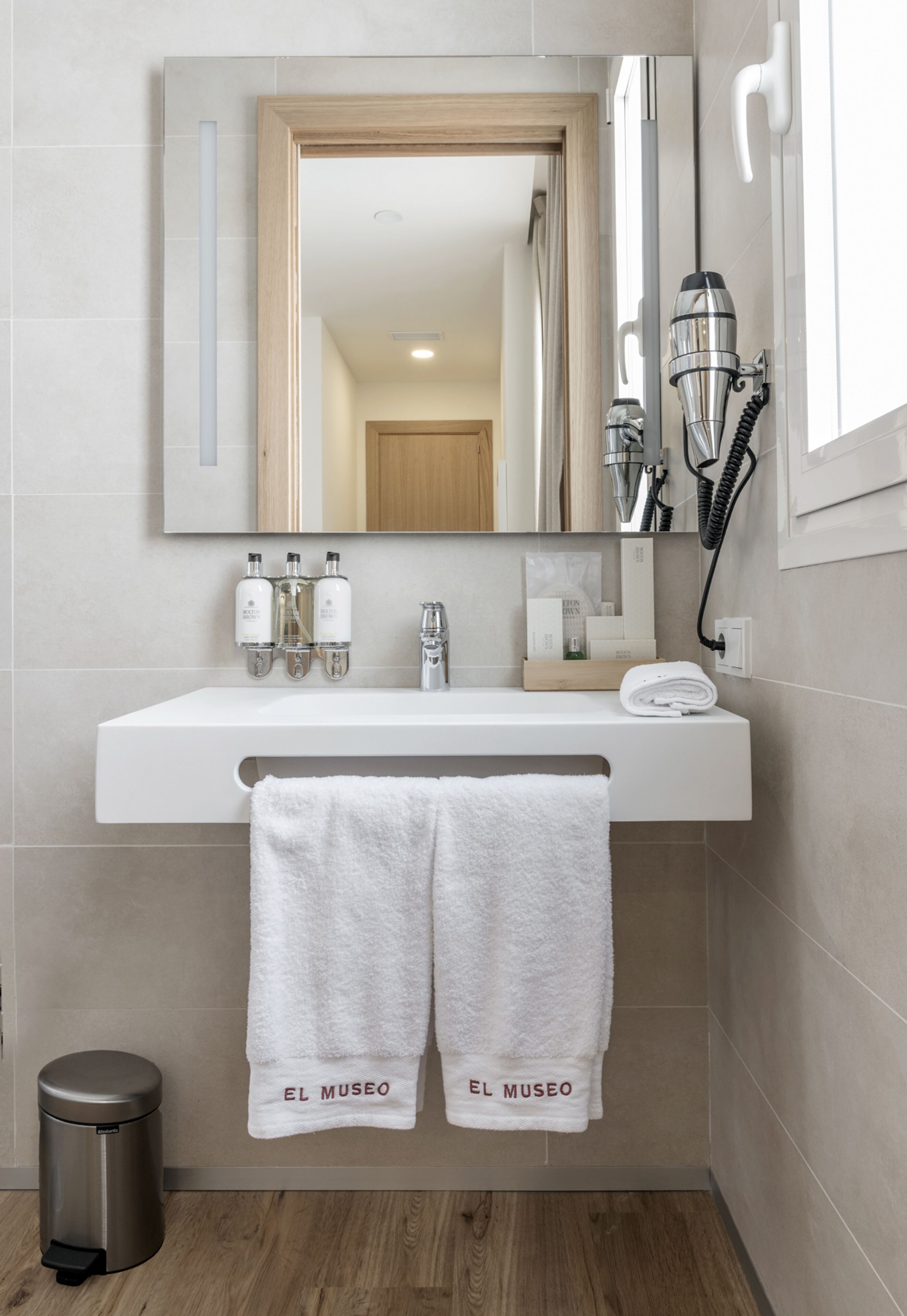 A modern bathroom with a white sink, mirror, and towel rack.
